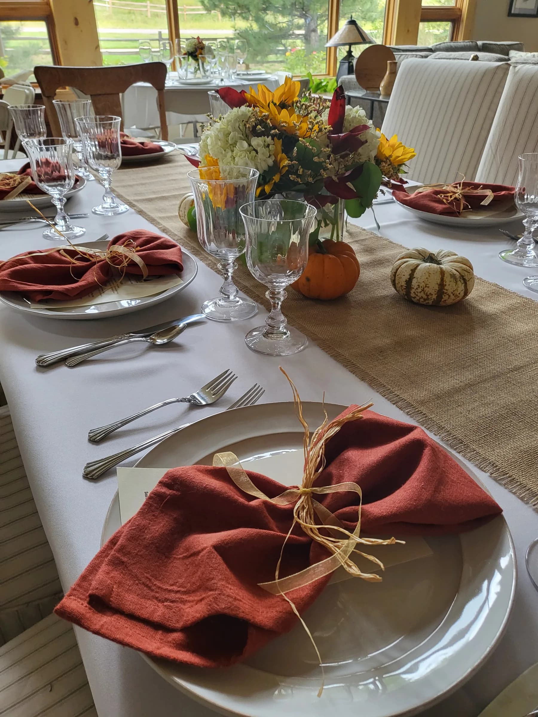 A table laid with rust napkins, sunflowers and small pumpkins