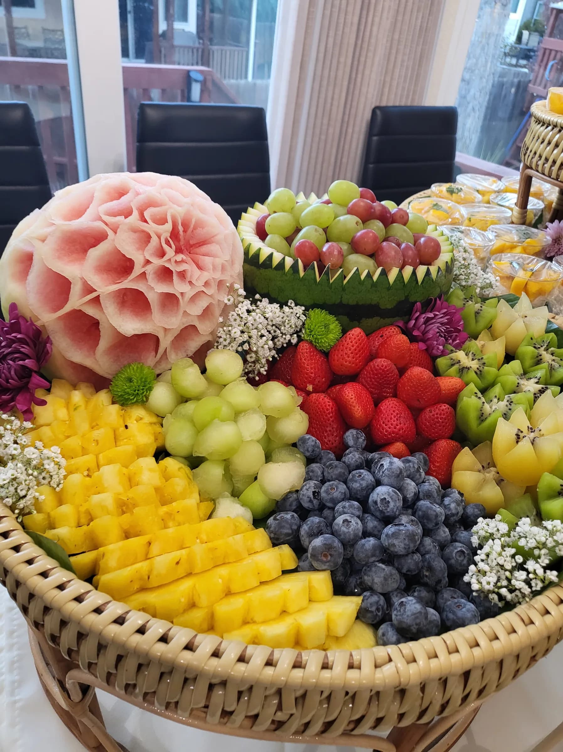 A carved fruit basket, melon flower at the centre, berries and pineapple around it