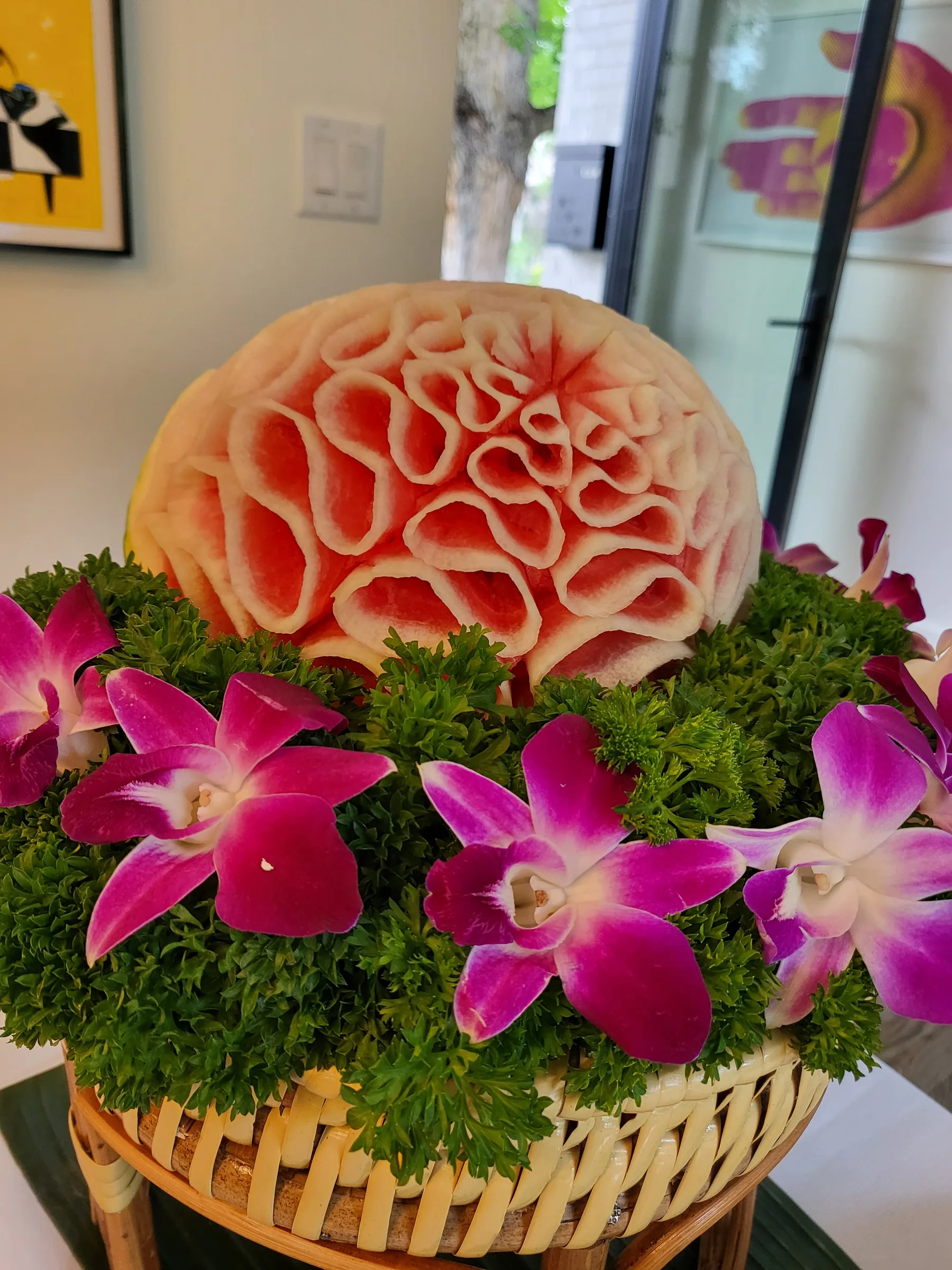 A melon carved into a flower and ringed with orchids