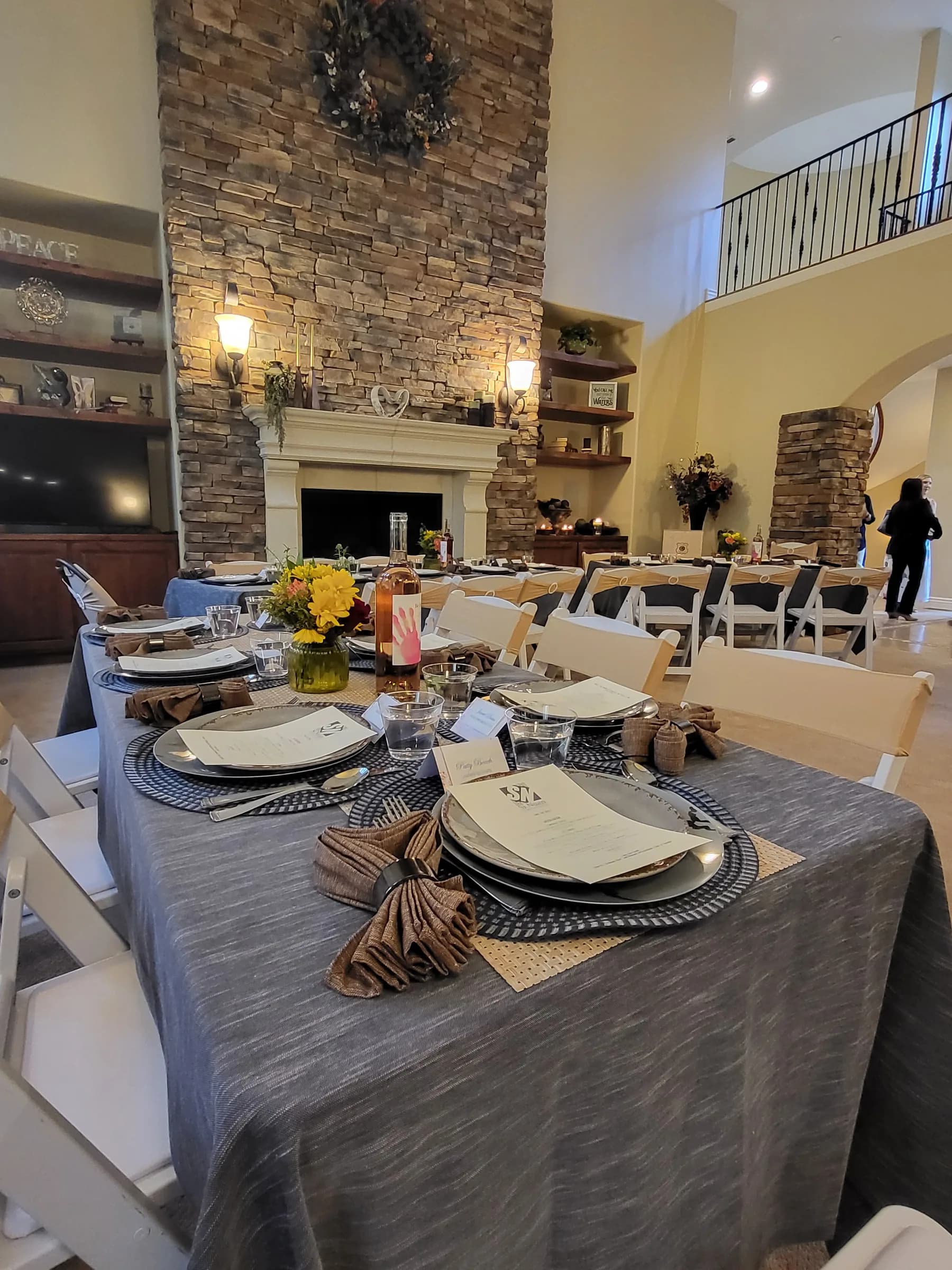 A long table set for dinner in a great room, folded napkins down its length
