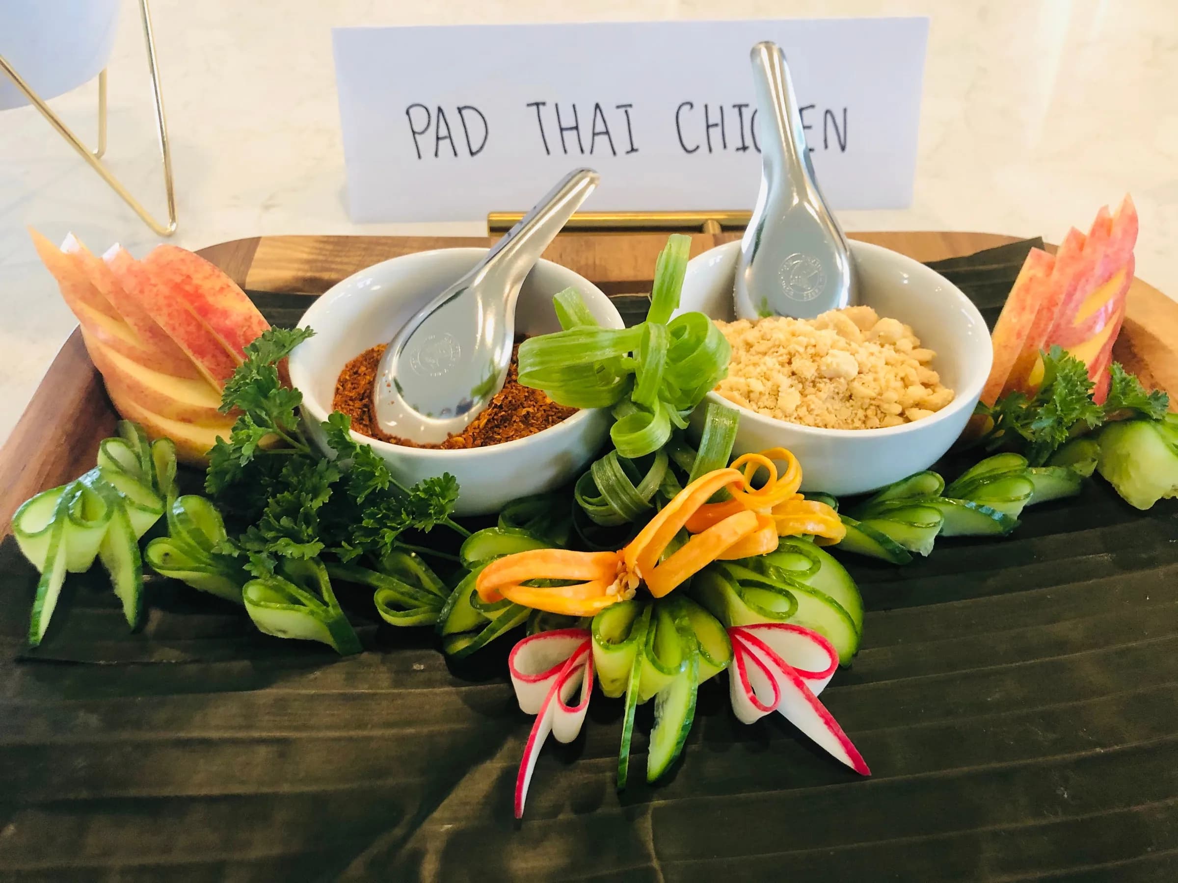 A Phad Thai station with condiment bowls and carved vegetable garnish